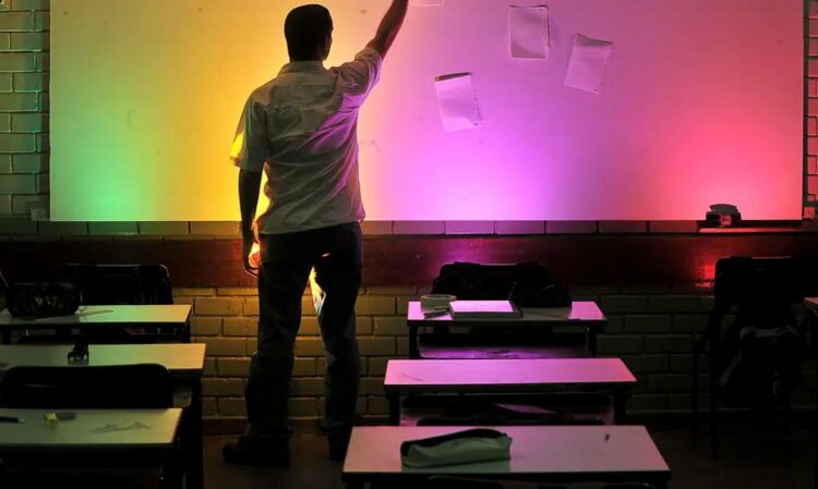 Professor em sala de aula com parede iluminada por luzes coloridas