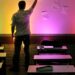 Professor em sala de aula com parede iluminada por luzes coloridas