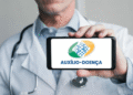 Médico segurando celular com a logo do Auxílio-Doença do INSS.