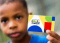 Criança segurando o cartão do Programa Bolsa Família.