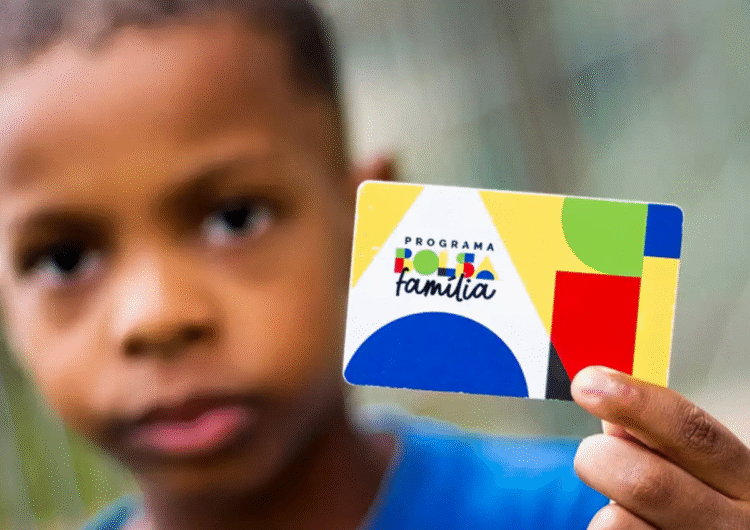 Criança segurando o cartão do Programa Bolsa Família.