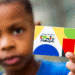 Criança segurando o cartão do Programa Bolsa Família.