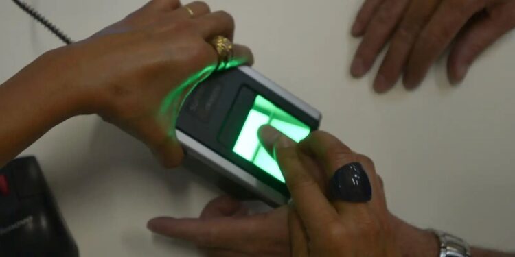 Pessoa realizando autenticação biométrica com leitor digital.