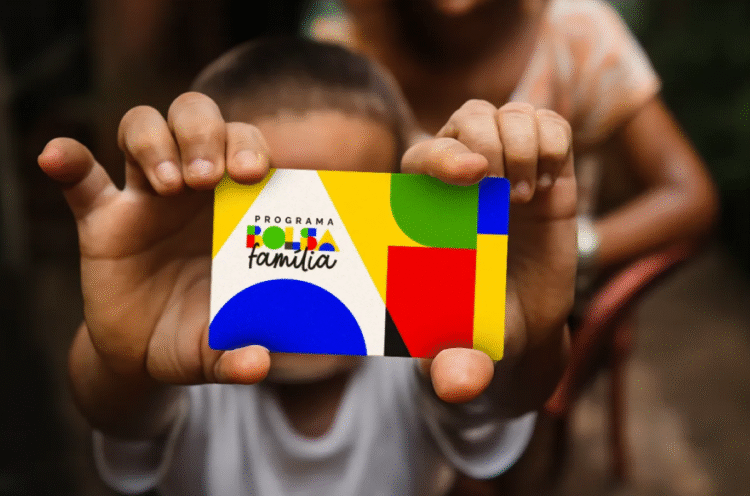 Bolsa Família de Setembro: criança segurando cartão colorido do programa.