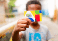 Cartão do programa Bolsa Família sendo segurado por uma criança