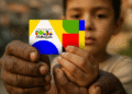Cartão do Programa Bolsa Família sendo segurado por mãos de uma criança e um adulto