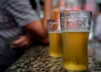 Copos de cerveja sobre balcão ilustram pauta sobre alcoolismo e INSS