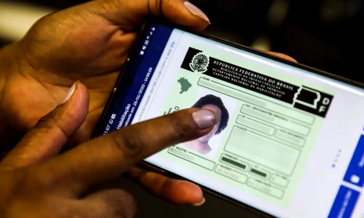Pessoa acessando a versão digital da CNH em um celular, com dedo apontando para a tela