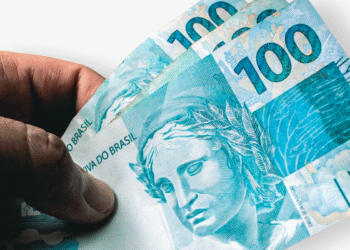 Pessoa segurando notas de 100 reais.