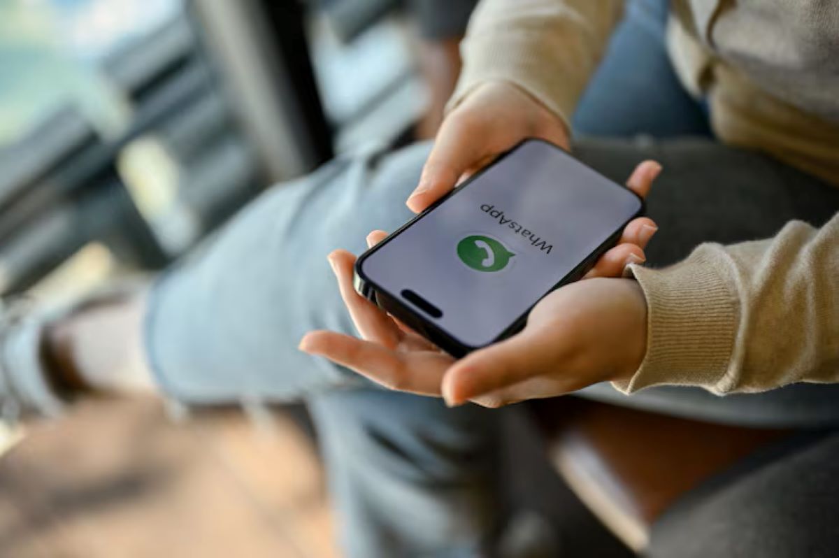 Mãos segurando um smartphone com o aplicativo WhatsApp aberto, simbolizando a comunicação digital e atendimento online.