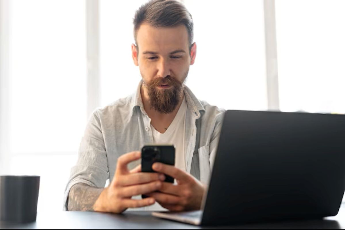 Homem usando celular enquanto verifica informações sobre o 13º salário.