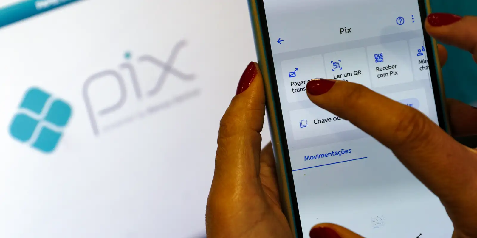 Usuária tocando na tela de um aplicativo de banco na área de transações Pix, ilustrando a expectativa dos clientes com o novo calendário de regulamentação e as datas de lançamento do Pix Parcelado pelo Banco Central.
