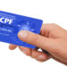 Mão de uma pessoa segurando um cartão de CPF azul com a inscrição ‘Cadastro de Pessoas Físicas’, simbolizando o golpe no CPF.