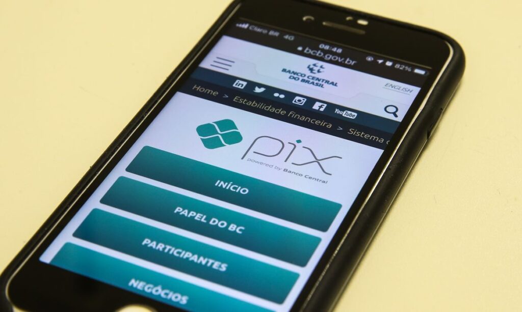 Celular exibindo o site do Banco Central, com o logo do Pix em destaque.