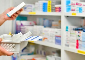 Farmacêutico organizando medicamentos em uma prateleira de farmácia.