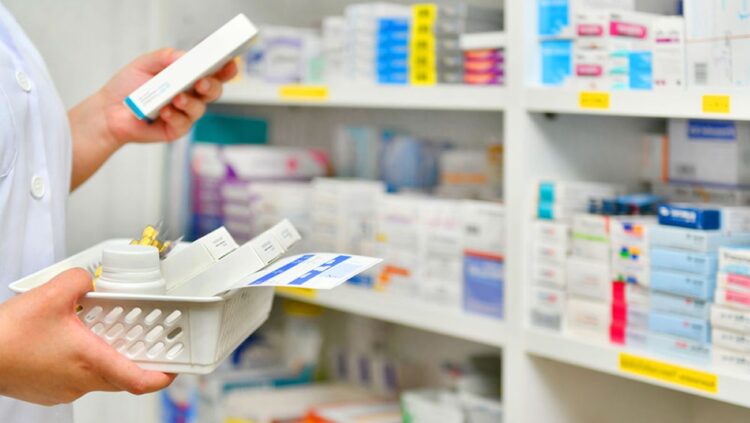 Farmacêutico organizando medicamentos em uma prateleira de farmácia.