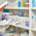 Farmacêutico organizando medicamentos em uma prateleira de farmácia.