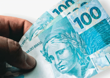 Pessoa segurando notas de 100 reais.