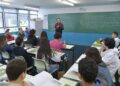 Professor ensinando em sala de aula com vários alunos atentos