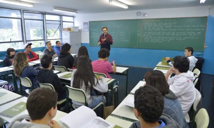 Professor ensinando em sala de aula com vários alunos atentos