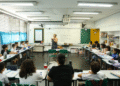 Uma professora, em uma sala de aula, dando uma palestra para seus alunos, simbolizando a importância da educação e do trabalho docente.