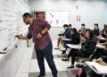 Professor explicando conteúdo na lousa em sala de aula, com alunos atentos