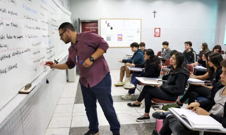 Professor explicando conteúdo na lousa em sala de aula, com alunos atentos