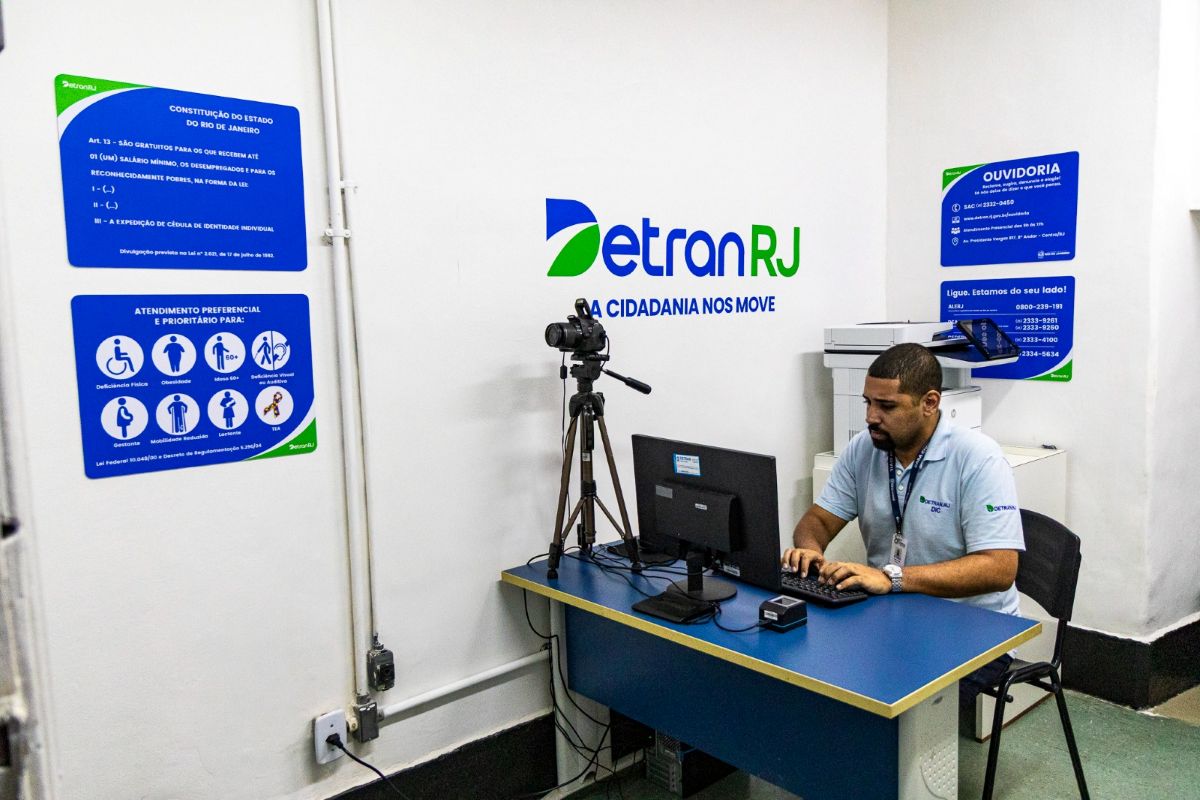 Atendimento no Detran RJ para emissão de carteiras de identidade, com equipe realizando o processo.