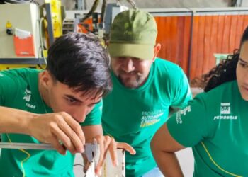 Jovens e adultos participando de uma atividade prática ou treinamento profissional em uma oficina, com o logo da Petrobras em suas camisetas, simbolizando qualificação e autonomia.