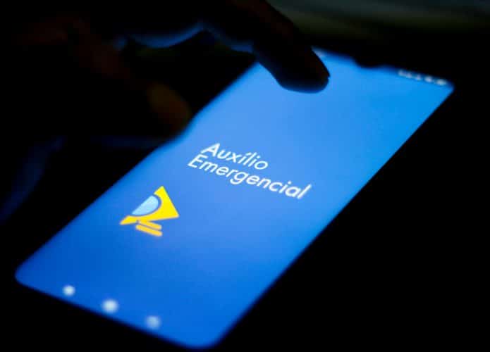 Tela de smartphone exibindo o logo do Auxílio Emergencial em fundo azul.