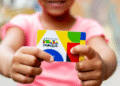Criança segurando cartão do Programa Bolsa Família com design colorido.