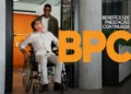 Homem em cadeira de rodas, sorrindo e recebendo ajuda para entrar em um ambiente, destacando o BPC (Benefício de Prestação Continuada) para pessoas com deficiência.