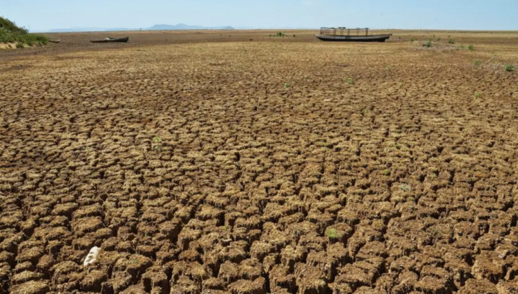 Seca castiga RN: 65 cidades entram em emergência e Bolsa Família pode ser antecipado 1 Solo rachado e seco de um leito de rio ou açude no sertão, com barcos abandonados ao fundo, evidenciando a seca severa