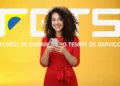 Mulher sorridente com celular em fundo amarelo, com a logo e texto FGTS em destaque. Imagem representa a consulta e agendamento do Saque-Aniversário FGTS 2025 com as novas datas confirmadas.