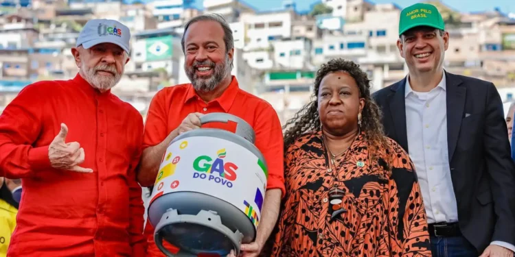 Quatro pessoas, entre elas homens e uma mulher, seguram botijão do programa Gás do Povo com expressão alegre
