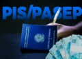 Carteira de Trabalho e Previdência Social com notas de cem reais, simbolizando o pagamento do PIS/Pasep.