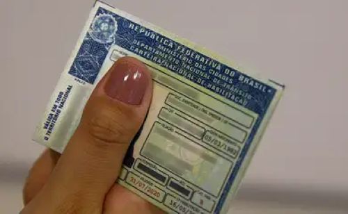 Mão segurando a Carteira Nacional de Habilitação (CNH) no formato impresso, representando o documento final obtido após o cumprimento dos requisitos básicos de idade, alfabetização e exames médicos.
