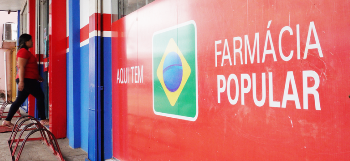Fachada de uma unidade do programa Farmácia Popular com a placa "Aqui Tem", representando o local de retirada de medicamentos gratuitos para cadastrados no CadÚnico.