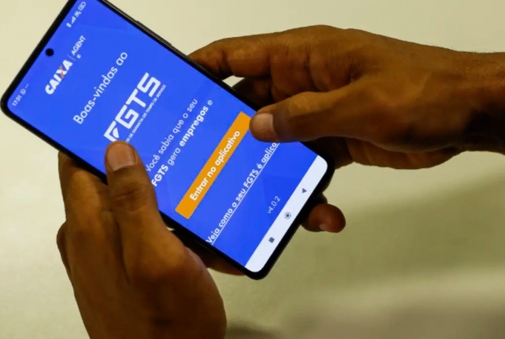 Mulher segurando celular com o aplicativo do FGTS aberto na tela.