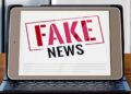 Tablet com a frase 'FAKE NEWS' em carimbo vermelho e preto, desmentindo a informação de R$ 5 mil para mães do Bolsa Família.