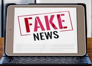 Tablet com a frase 'FAKE NEWS' em carimbo vermelho e preto, desmentindo a informação de R$ 5 mil para mães do Bolsa Família.