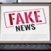 Tablet com a frase 'FAKE NEWS' em carimbo vermelho e preto, desmentindo a informação de R$ 5 mil para mães do Bolsa Família.
