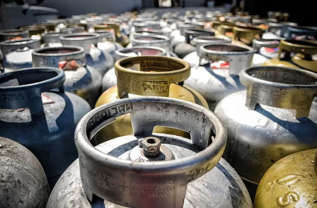 Vários botijões de gás empilhados em um depósito.