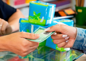 Pessoa entrega documento de identidade em balcão de UBS para retirar absorventes gratuitos.