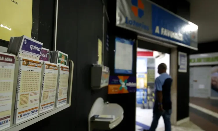 Variedade de bilhetes de loteria organizados em display em ponto de venda de loterias Caixa