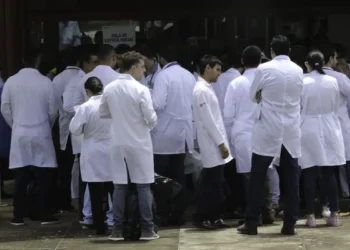 Grupo de médicos com jalecos brancos reunidos na entrada da sala de espera de hospital ou clínica