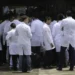 Grupo de médicos com jalecos brancos reunidos na entrada da sala de espera de hospital ou clínica