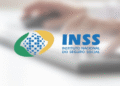 Logotipo do INSS sobre fundo desfocado com teclado.