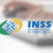 Logotipo do INSS sobre fundo desfocado com teclado.