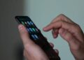 Usuário utilizando o dedo para navegar na tela de um smartphone com diversos ícones de aplicativos, simbolizando o acesso a plataformas de apostas (BETs) e as novas restrições federais.